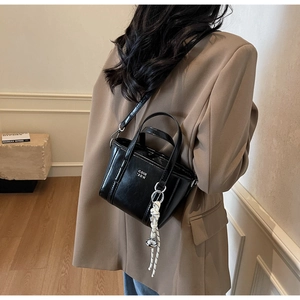 Chic black bucket bag with COIH 2DN logo and woven charm detail shown on model back