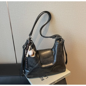 Detail shot of vintage leather tote bag with magnetic flap and baseball bat charm accessory