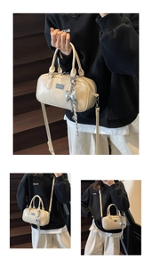 Detail view of cream Boston bag featuring silver bow charm and adjustable strap