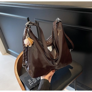 Detailansicht der dunkelbraunen Lackleder-Tote mit silbernem Dreiecks-Logo-Schild