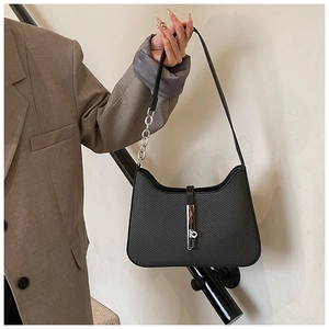 Detail of black textured hobo bag with silver chain strap and metal lock on model