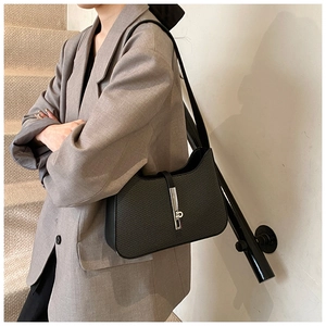 Detail of black woven leather shoulder bag with sleek silver metal buckle and texture