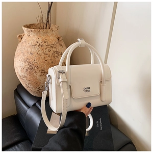 Detailed view of cream white leather mini handbag with silver logo and round handle