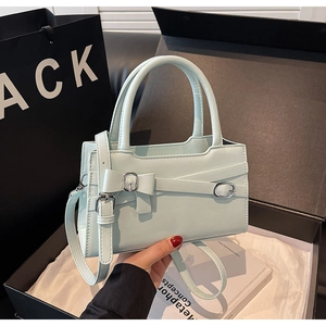 Detail view of mint green handbag featuring a bow design and metallic buckle accents
