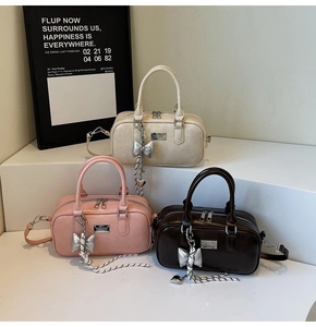 Detailed close-up of fashion bowling bags in beige, pink and brown with silver bow charms