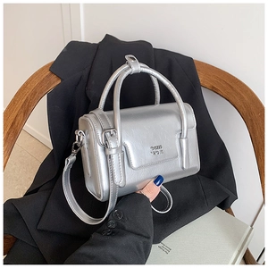 Detail of silver metallic square handbag with CCIIH 2DN logo on a black suit backdrop