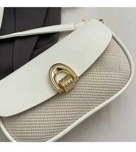 Close-up of woven texture and golden U-shaped hardware lock on the crossbody bag