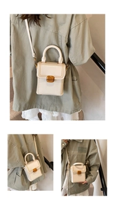 Detail view showing cream mini box bag with gold metal lock and detachable shoulder strap
