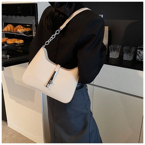 Detail of off-white woven shoulder bag featuring a silver metal clasp and chain strap