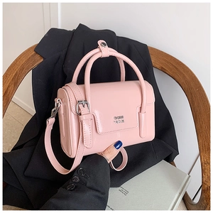Detail of pink glossy leather handbag with metal logo and adjustable shoulder strap