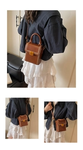 Detail of caramel brown leather box bag with white stitching and golden metal lock