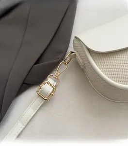 Detailed macro view of golden metal hardware and white leather strap of the square bag