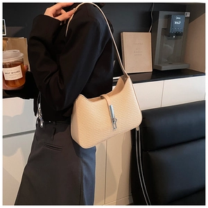 Detail of beige hobo bag showing woven leather texture and silver buckle on shoulder strap