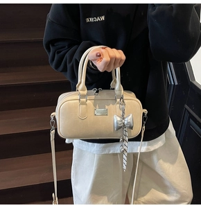 Detailed view of beige PU leather bowling bag with silver bow charm and metal plaque