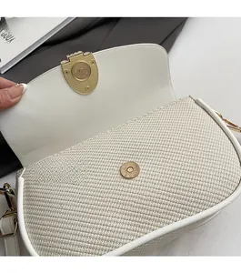 Close-up of magnetic snap closure on beige woven flap crossbody bag with leather trim