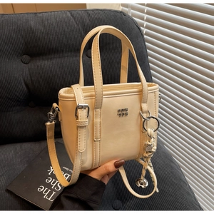 Close-up of cream beige bucket bag with silver hardware and woven rope accessory