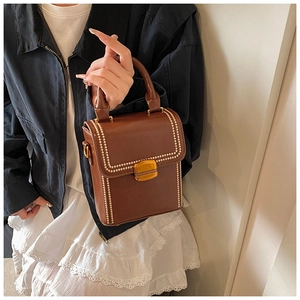 Detail view of brown vintage box bag featuring gold bead trim and square metal lock