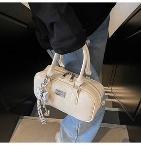Close-up of cream bowling bag showing PU leather texture and silver bow charm