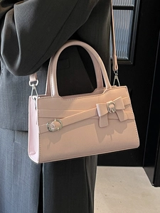 Pink PU leather square handbag with bow and silver buckle detail on a grey suit jacket