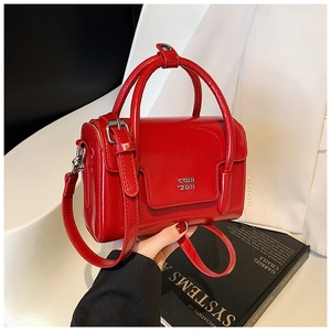 Close-up of a vibrant red oil wax leather handbag with shiny finish and silver logo detail