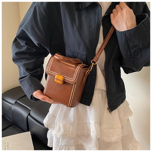 Detailed view of a brown vintage mini box bag with pearl trim and golden twist lock