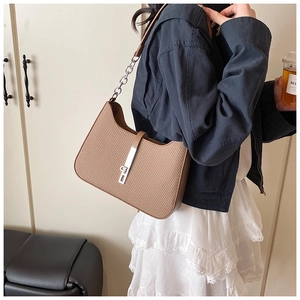 Detail of brown woven leather texture and silver metal lock on shoulder underarm bag