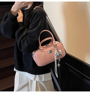 Detailed shot of pink bowling handbag with silver bow charm and adjustable strap