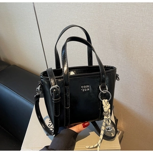 Detail of black glossy mini bucket bag with silver hardware and adjustable strap