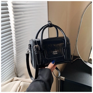 Detail of glossy pleated black leather bag with metal buckle strap and COIN 2DN lettering