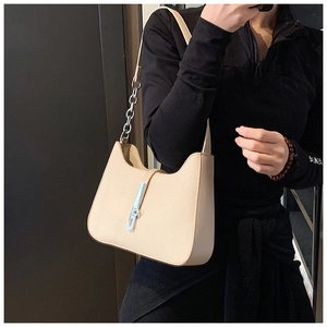 Detail of beige shoulder bag with silver chain strap and metal buckle on leather texture