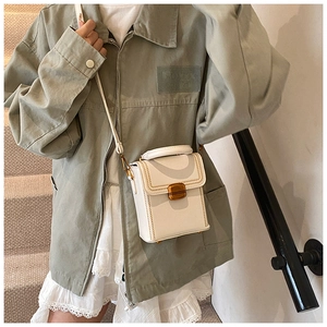 Detailed view of a white leather box bag featuring golden hardware and decorative stitching