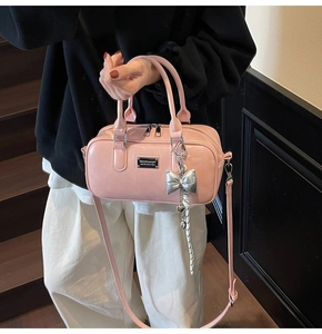 Pink bowling bag with silver bow charm and adjustable strap shown by a model