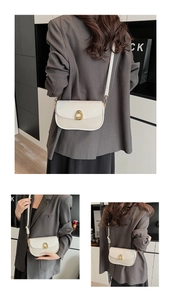 Detail view of the beige square crossbody bag showing woven texture and gold horseshoe buckle
