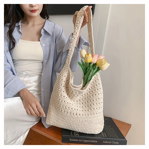 Dettaglio della borsa tote in crema intrecciata a mano con trama a maglia e tracolla