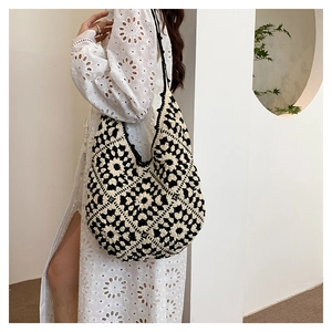 Detail shot of a handmade black and white crochet tote bag with daisy flower patterns