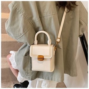 Detail of the elegant white leather box bag featuring gold stitching and metal twist lock