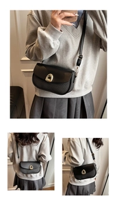 Three-way view of a black saddle bag with golden horseshoe clasp and woven texture details