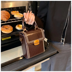Detailed view of dark coffee box bag with cream bead trim and vintage gold lock