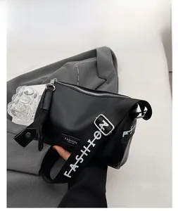 Close-up of black lychee grain texture bag with a wide fashion strap on a grey blazer
