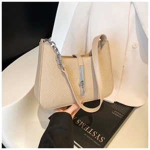 Detail of beige woven underarm bag with silver metal buckle and chunky chain strap