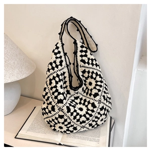 Detail of crochet tote bag featuring black and white granny square pattern on a book