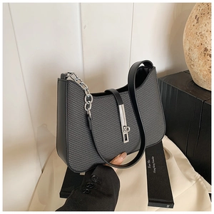Detail of black woven underarm bag with silver twist lock and chain strap