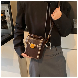 Detail view of brown leather crossbody box bag featuring white bead trim and gold lock