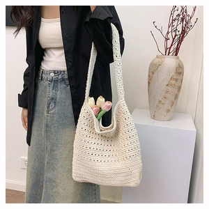 Dettaglio ravvicinato della borsa tote intrecciata a mano con motivi crochet bianco crema