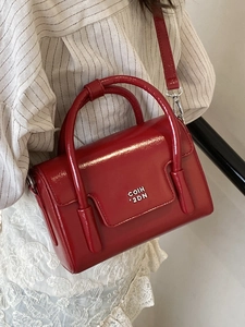 Vintage red oil wax leather handbag with top handles and crossbody strap worn by a model