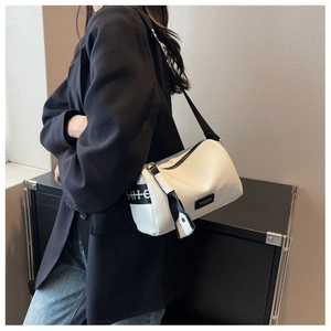 Close-up of white lychee leather texture on cylindrical bag with black wide shoulder strap