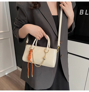 Détail d'un sac à main blanc en cuir ciré avec chaîne coeur dorée et cordon de décoration