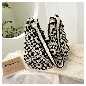 Close-up of bohemian crochet tote bag featuring black and white floral knit texture