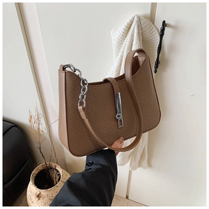 Close-up of brown woven shoulder bag with stylish silver metal chain detail
