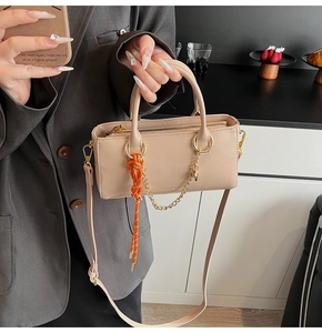 Détail du sac à main carré en similicuir beige avec breloque corde orange et chaînette